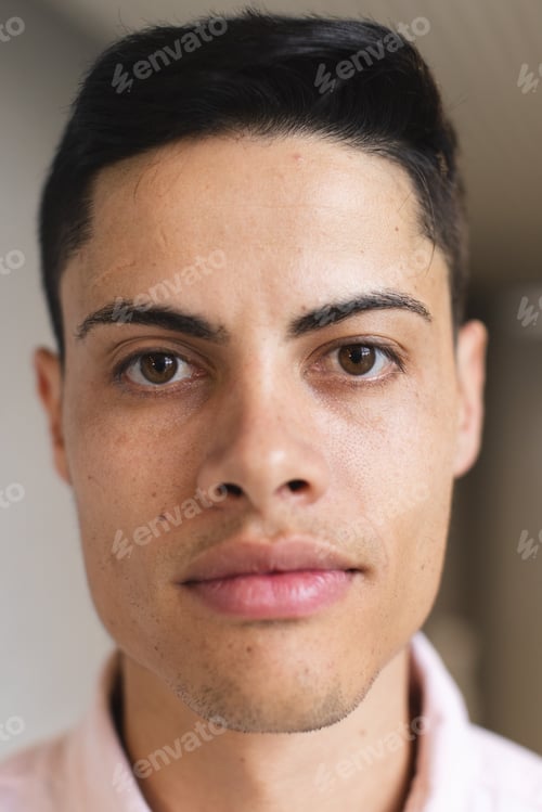 Preview: Biracial man with short dark hair looks at camera in modern office