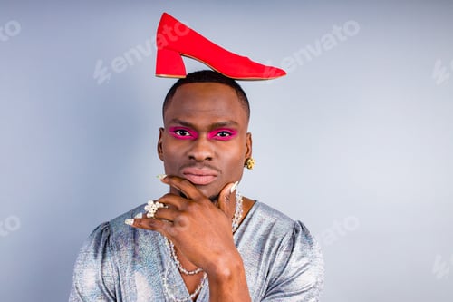 Preview: african american cross dressing trans drag queen holding a red shoe in studio white wall