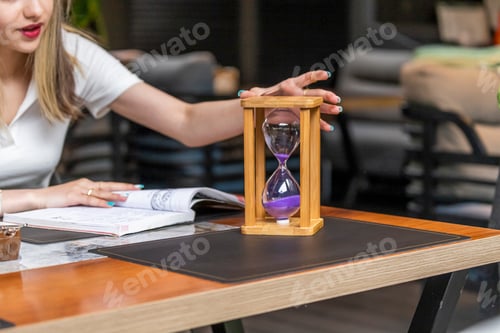 Preview: Cute girl holding a hourglass at the cafe