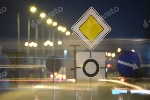 Preview: Roundabout road signs with blurred cars on city street traffic at night. Urban transportation
