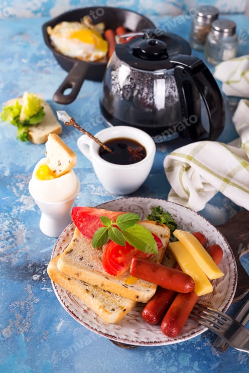 Preview: English breakfast. Fried eggs, sausages, toasts, tomatoes on stone table.