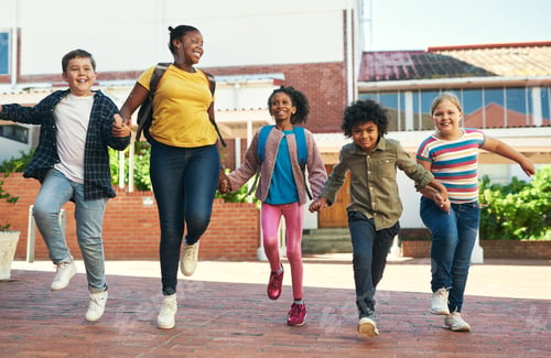 Preview: Full length shot of a diverse group of children skipping outside during recess at school