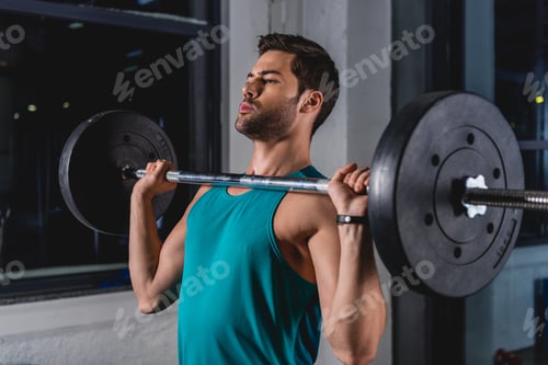 Preview: sportsman lifting barbell in sports hall