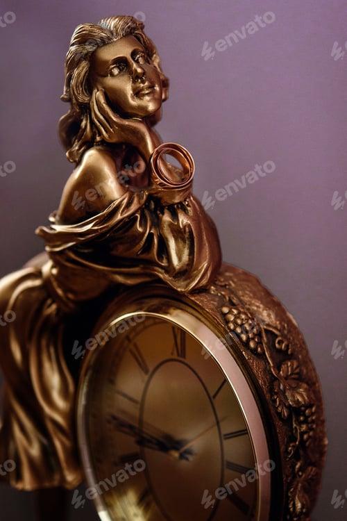 Vista previa: stylish pair of golden wedding ring on metal gold woman figurine with clock, time concept