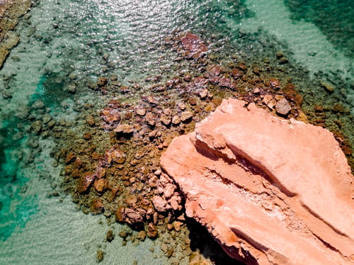 Preview: Aerial view of a natural rock jetty on the Mediterranean coast with transparent turquoise waters.