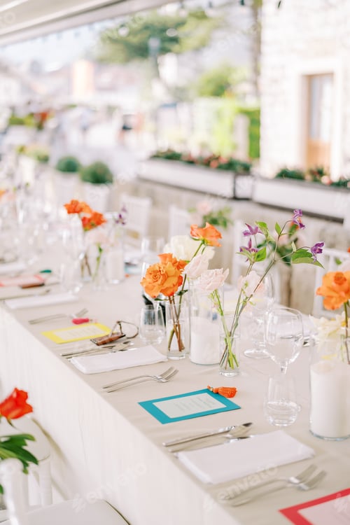 Preview: Long holiday table with colorful invitations and bouquets of flowers