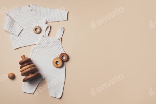 Preview: Newborn beige romper, sweater, pants, shoes, wooden toys on neutral backgroundd