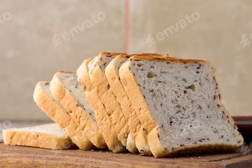 Preview: Sliced rectangular loaf of bread with flax grains on a wooden cutting board