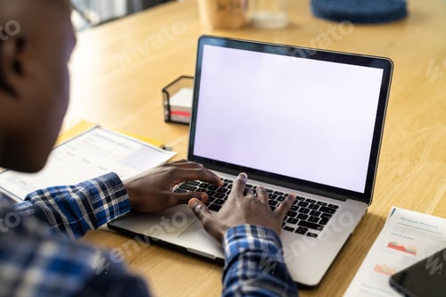 Preview: African american man sitting at table, using laptop with copy space on screen at home