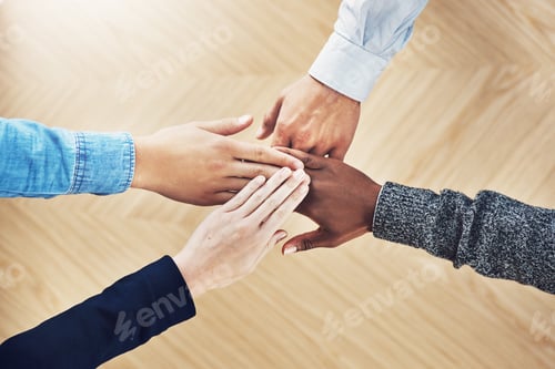 Preview: High angle shot of a group of unidentifiable businesspeople joining their hands together in unity