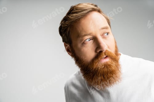 Preview: curious man with beard wearing white t-shirt looking away isolated on grey