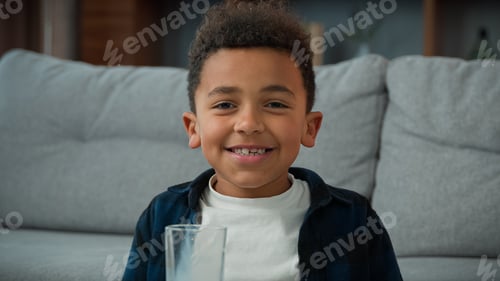 Preview: Head shot close up portrait little funny cute 10s kid boy ethnic child drink milk at home smiling to