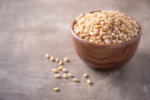 Preview: Shelled raw pine nuts in wooden bowl on wood textured background. Copy space. Superfood, vegan