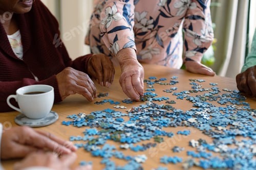 Preview: Hands of two diverse senior women and african american male friend doing puzzles