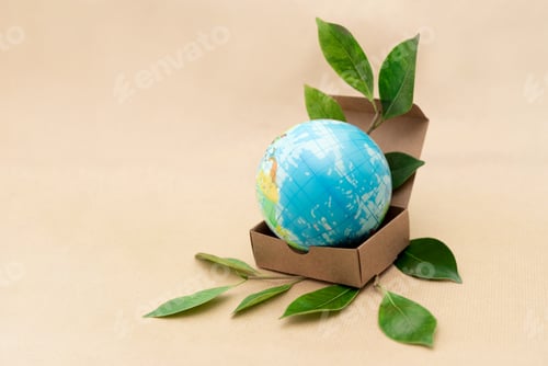 Preview: Mini Earth globe in an open cardboard box with green leaves on a beige background,