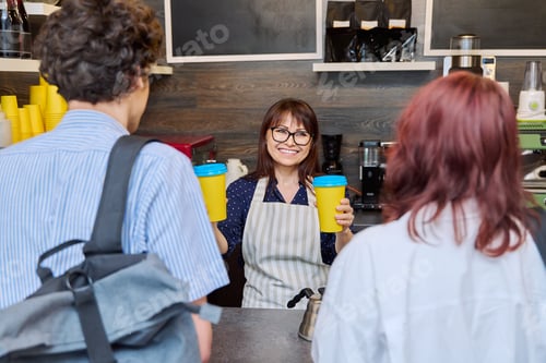 Preview: Female coffee shop worker serving customers giving paper cups of takeaway coffee