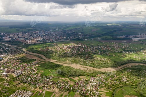Preview: Aerial view of town or village with rows of buildings and curvy streets between green fields