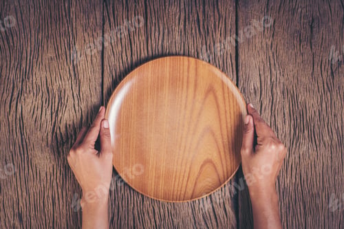 Preview: Top view hand holding plate on wood background