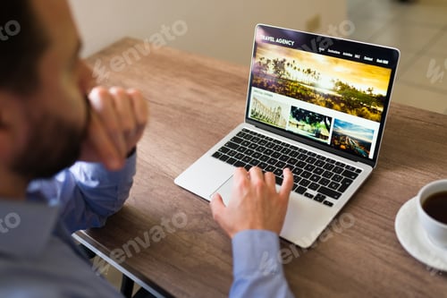 Preview: Attractive man looking at holiday tour options online