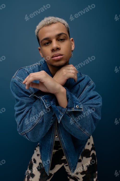 Preview: Stylish young man showcases fashionable denim jacket against blue background