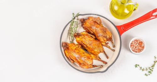 Preview: quail Baked quails in pan Cooked on a white background top view. copy space