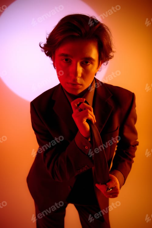 Preview: Stylish young man posing against an orange backdrop with a dramatic circular light