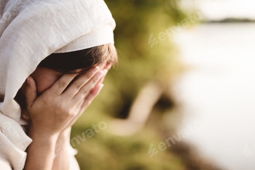 Preview: Closeup shot of a female wearing a biblical robe praying with a blurred background