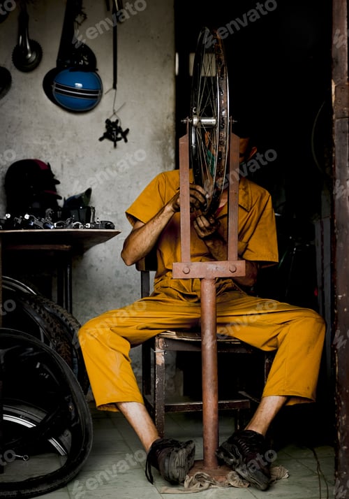 Preview: Vertical shot of a man repairing a bike wheel at a repair shop in Camaguey, Cuba
