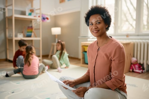 Preview: Smiling African American teacher at kindergarten looking at camera.