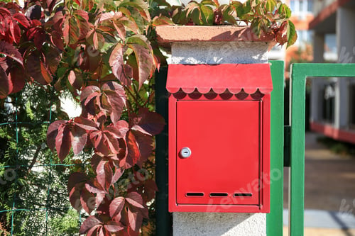 Preview: Red metal letter box on stone column near gate outdoors