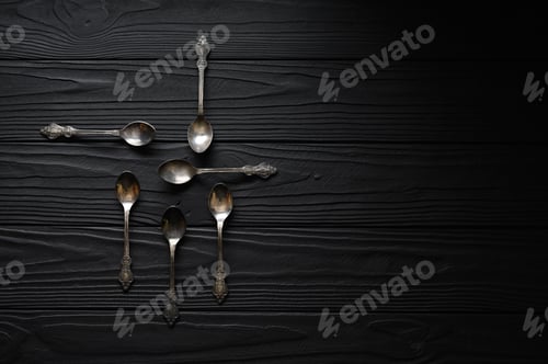 Preview: Directly above a shot of old spoons on a black table
