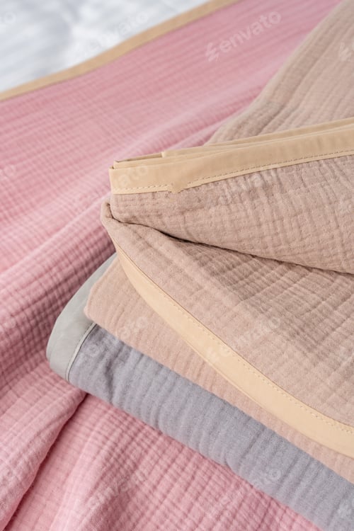 Preview: Folded Pink and Beige Blankets on a Grey and White Bed With Black Iron Headboard
