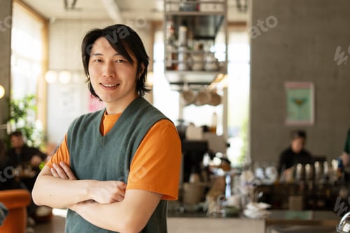 Preview: Confident barista smiling with arms crossed in cafe