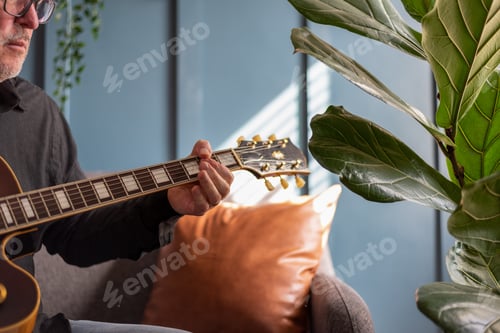 Preview: Man playing a vintage guitar at home in natural light