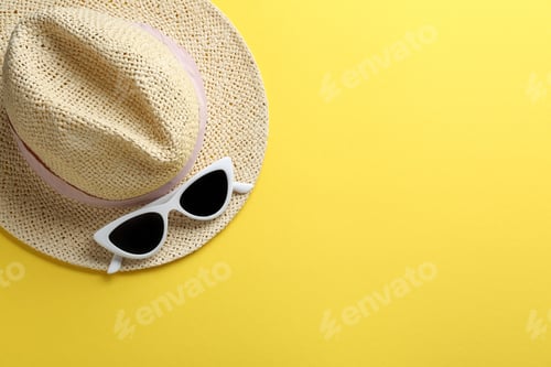Preview: Women's sunglasses and hat on yellow background, top view. Space for text