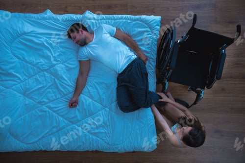 Preview: The woman caring about disabled man on the bed. view from above
