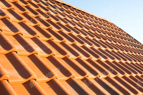 Preview: Overlapping rows of yellow ceramic roofing tiles covering residential building roof