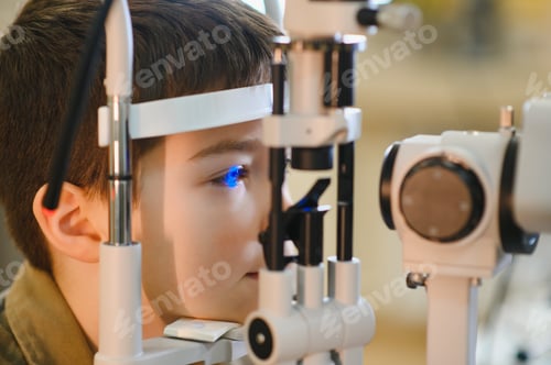 Preview: Ophthalmologist examining boy's vision with modern equipment in clinic