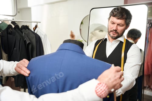 Preview: Tailors trying on garment on dummy in workshop