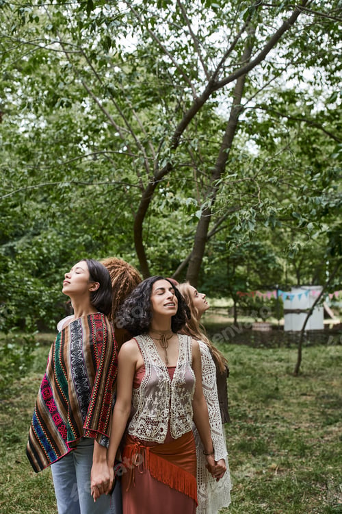 Preview: smiling interracial women holding hands while standing back to back in retreat center