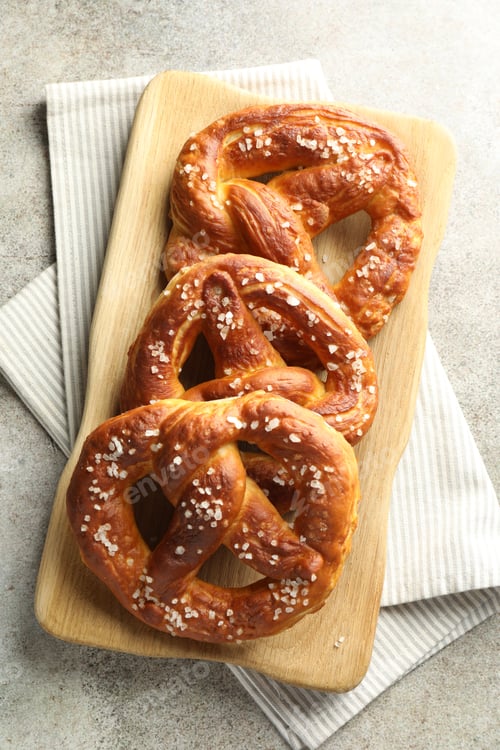 Preview: Tasty pretzels with salt on grey table, top view