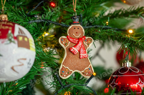 Preview: Gingerbread hanging on christmas tree with balls and lights.