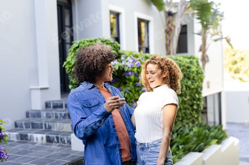 Aperçu: Young diverse couple laughing and enjoying conversation outdoors in garden setting