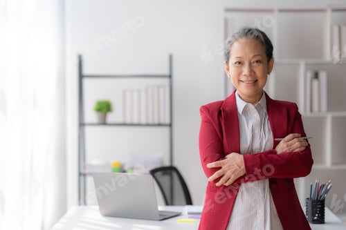 Preview: Asian senior businesswoman crossed arms smiling happily at office.
