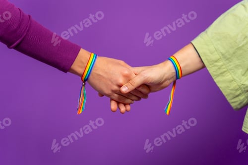 Preview: Two lesbian woman holding hands wearing lgbt rainbow bracelet