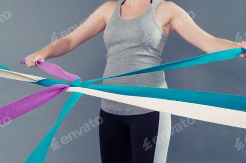 Preview: Young woman using coloured bands, grey background