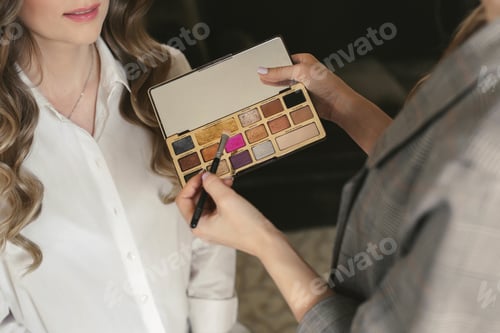 Preview: Young beautiful bride applying wedding makeup from a makeup artist. The morning training