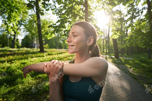 Preview: Smiling woman doing warm-up before training in nature