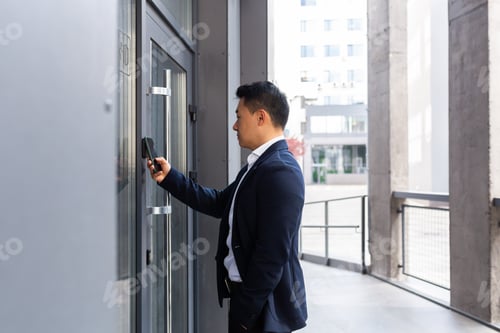 Preview: Successful Asian businessman opens the door of the office center using a smartphone