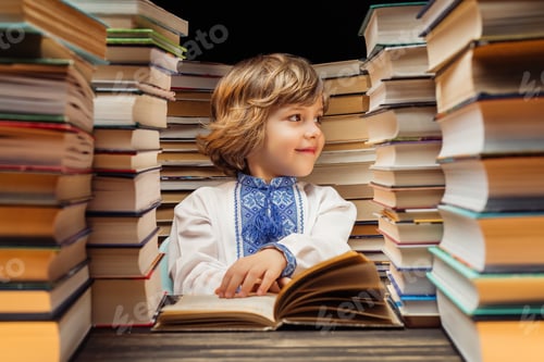Preview: Portrait of handsome little ukrainian child with book in library. Elementary school boy